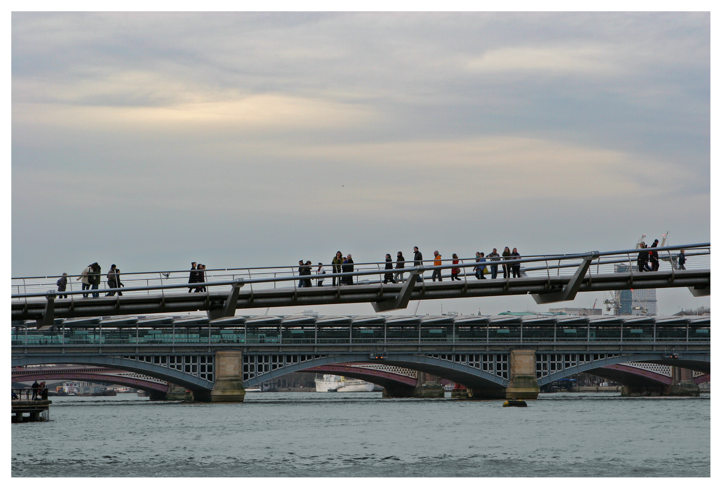 People on millenium bridge over the river Thames, London, England